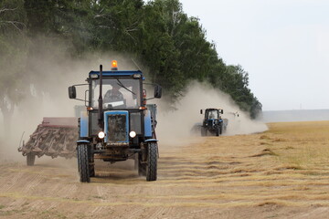Two tractor with harvester trailer fast drive in dust cloud on linen field edge, linum harvesting...