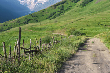 Fototapeta na wymiar Caucasian rural landscape. View of the road in Genaldon river gorge on sunny summer day. North Ossetia–Alania, Caucasus, Russia.
