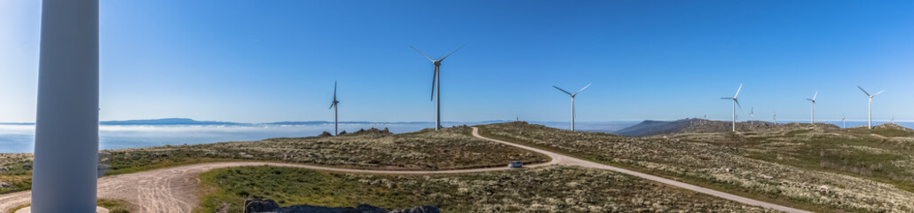 Ultra panoramic view at the Caramulo mountains, with wind turbines and blue sky, Serra da Estrela mountains as background, in Viseu - obrazy, fototapety, plakaty