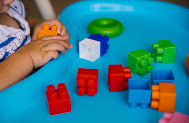 Obraz premium The child collects a multi-colored constructor. Children's classes in kindergarten or at home.