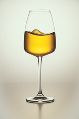 A close-up of crystal glass with white wine on the light background. Wavy surface, no splashes. Restaurant glassware, beverage, table setting, romance, passion, love, party, water splashes.