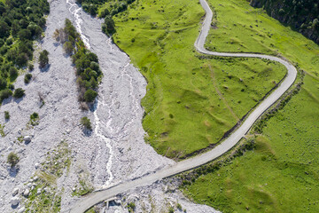 Aerial view of mountain road in Balkarsky Cherek river valley on sunny summer day. Kabardino-Balkaria, Caucasus, Russia.
