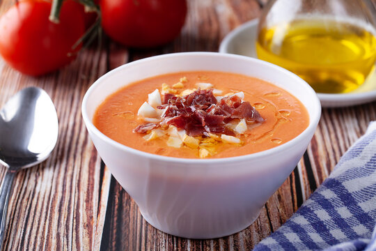 Bowl of salmorejo soup with boiled egg and serrano ham on rustic table