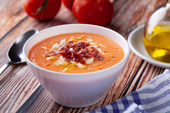Bowl of salmorejo soup with boiled egg and serrano ham on rustic table