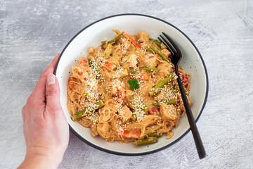 vegan thai stiry fry with peanut lime sauce and vermicelli noodles topped with sesame seeds, healthy plant-based food
