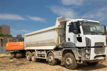 dump truck at work at a construction site. The process of loading soil or crushed stone with an excavator for further transportation on a construction machine. Commercial vehicles