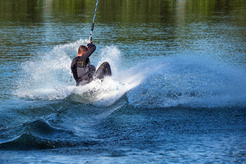 Obraz premium A man wakeboarding on a lake on summer day in a life jacket. Soft focus. Action blur.