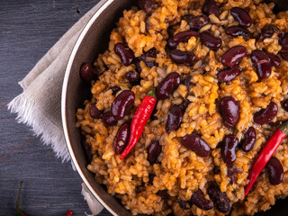 Portion of mexican rice with beans in a plate with very hot chili peppers, close-up, top view on a napkin
