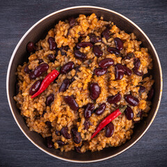 Serving of Mexican Spanish rice with beans in a plate with very hot chili peppers, close-up, top view