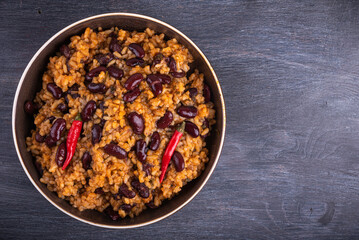 Fototapeta premium Mexican tomato rice with beans in a plate with very hot chili peppers, close-up, top view, copy space - Hispanic cuisine.