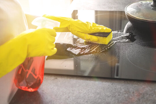 Hand in yellow rubber glove washes a electric stove on a sunny day, kitchen cleaning concept background photo