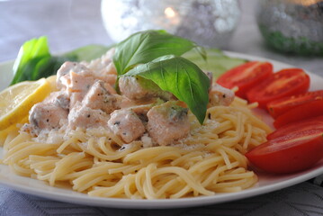 Italian cuisine: spaghetti with salmon, cream cheese and basil and tomatoes close-up on plate