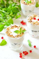 Dessert in a glass on a light background, decorated with nuts, mint leaves and berries. Creamy jelly. Parfait.