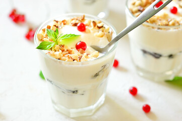 Dessert in a glass on a light background, decorated with nuts, mint leaves and berries. Creamy jelly. Parfait.