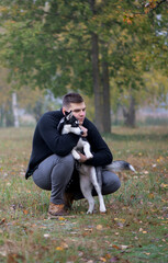 Naklejka na ściany i meble Young man pet owner with dog in autumn park