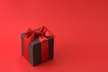 Black gift box with red bow on red background