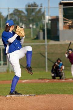 Mixed race female baseball pitcher on sunny baseball field preparing to throw ball during game