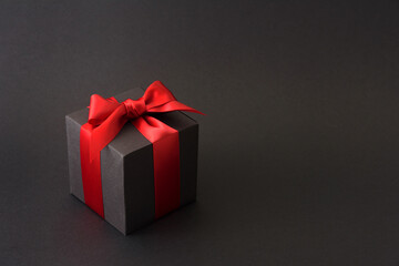 Black gift box with red bow on black background