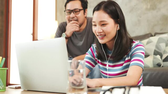 Asian young woman working on laptop computer sitting at home with a dog pet and managing her business via home office during Coronavirus or Covid-19 quarantine.Cozy office workplace,E learning concept