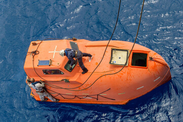 seamen hooking up lifeboat on the sea