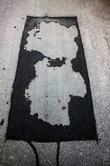 Wet spots on the gray asphalt in the form of a cartoon bear and a human head. It is two meanings in one form. Illustration of visual illusion - pareidolia.