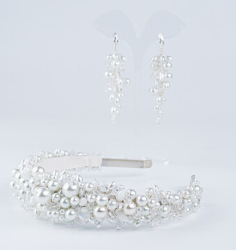On a white background, a blurred image of earrings and jewelry with pearls for the hair of the bride.
