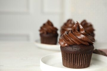 Plate with delicious chocolate cupcake on white table. Space for text