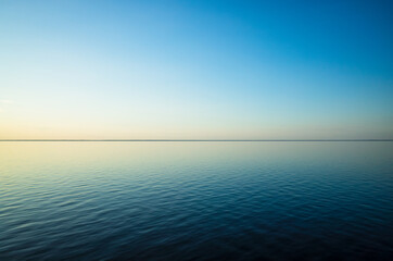Tranquil minimalist landscape with a smooth blue sea surface with calm waters with a horizon and...