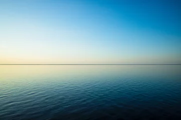 Papier Peint photo Pool Tranquil minimalist landscape with a smooth blue sea surface with calm waters with a horizon and clear skies. Simple beautiful natural calm background. Copy space.