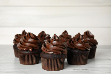 Delicious chocolate cupcakes with cream on white wooden table. Space for text