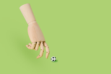 Hand of wood playing with a soccer ball on a green background. football and sport concept.