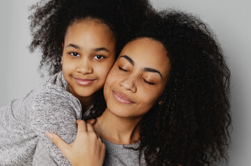 Portrait of young girl embracing mother from behind.