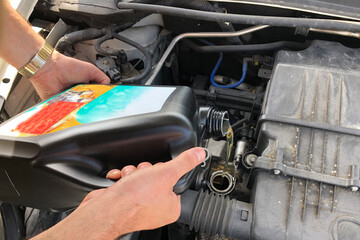 a man pours oil bought in a supermarket into his car