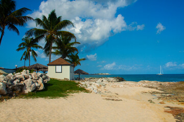 small white house on the beach on the island caribbean sea , palm trees and yellow sand