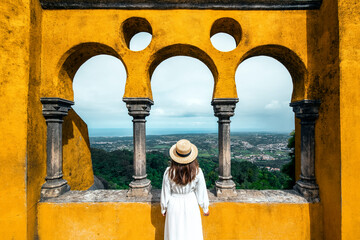 Traveler woman visiting Pena Palace in Sintra, Lisbon, Portugal. Famous landmark. The most beautiful castles in Europe - obrazy, fototapety, plakaty