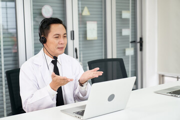 Asian male doctor waer headset and descript to patient in laptop , Online healthcare consultant service