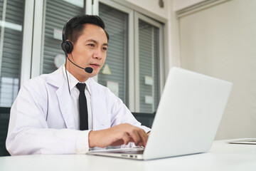 Asian senior male doctor waers headset and look at laptop , Online call center healthcare medical...