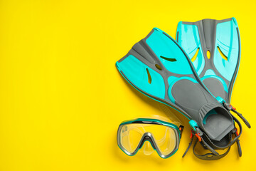 Pair of turquoise flippers and mask on yellow background, flat lay. Space for text © New Africa