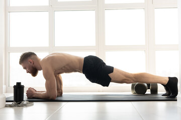 European sportsman doing plank on fitness mat