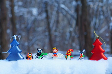 Figurines of fairy-tale characters in the winter forest. An angel with a gift, a dwarf, a rabbit...