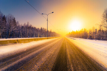 Sunrise on a clear winter morning, empty highways in snow. View from the road. Coniferous forest. Russia, Europe. Beautiful nature.