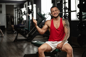 Fototapeta premium Portrait of man bodybuilder in red shirt in gym