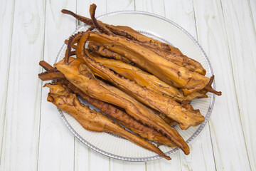 Octopus tentacles (Latin Octopoda) are brown on a round plate with a wooden table background. Food is a delicacy snack for beer.