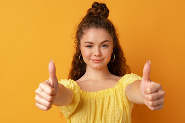 Young happy cheerful woman showing thumb up .in studio