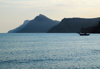 Boat moored on the bay of Portman and mountains in the background