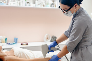 Professional beautician doing laser treatment and removing hair from female hand