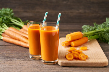 Fresh carrot juice in glasses on a  rustic wooden table, selective focus.