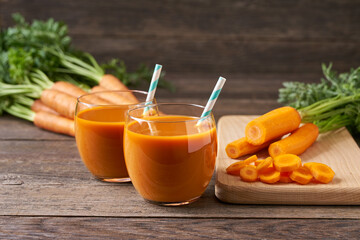 Fresh carrot smoothies and vegetables on a rustic wooden table, close-up.
