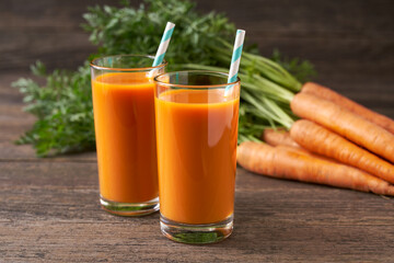 Fresh carrot juice in glasses on a  rustic wooden table, selective focus.
