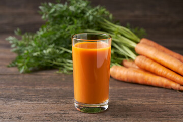 Fresh carrot juice in glasses on a  rustic wooden table, selective focus.